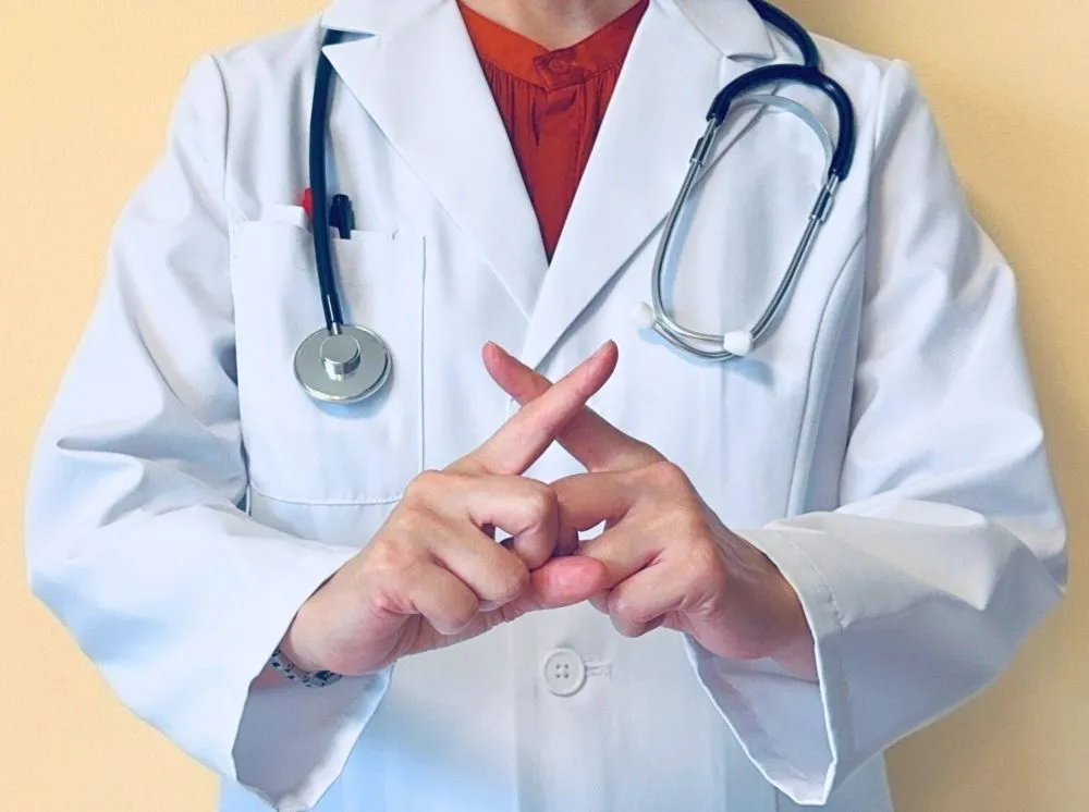 白衣を着た女性中医師が指でバツを作って「治療中は性行為禁止」を表現