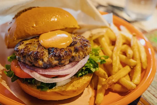 ハンバーガーとポテトがのったプレートをクローズアップしたファーストフードの画像
