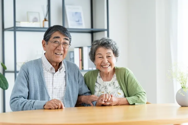 リビングでくつろぎながら笑顔で寄り添う高齢夫婦