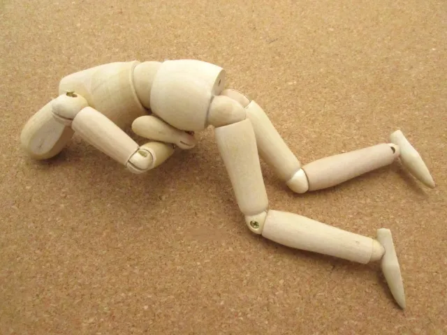 木製人形が心臓発作を表現して胸を抑えながらうつ伏せで倒れている様子