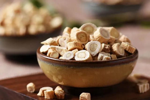 土色の陶器の器からこぼれた黄耆（オウギ）の乾燥スライス 漢方薬材