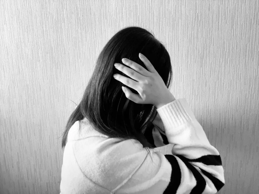 耳の奥が痛くて両手で耳を塞いでいる女性の横顔（白黒写真）