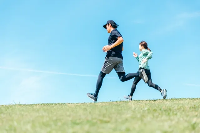緑道を軽やかにランニングする男女。日常的に歩く・走る習慣で内臓機能の回復をサポートしている様子。