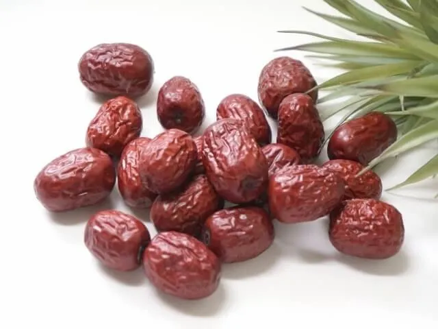 乾燥した大棗（なつめ）と緑の葉が並んだ様子