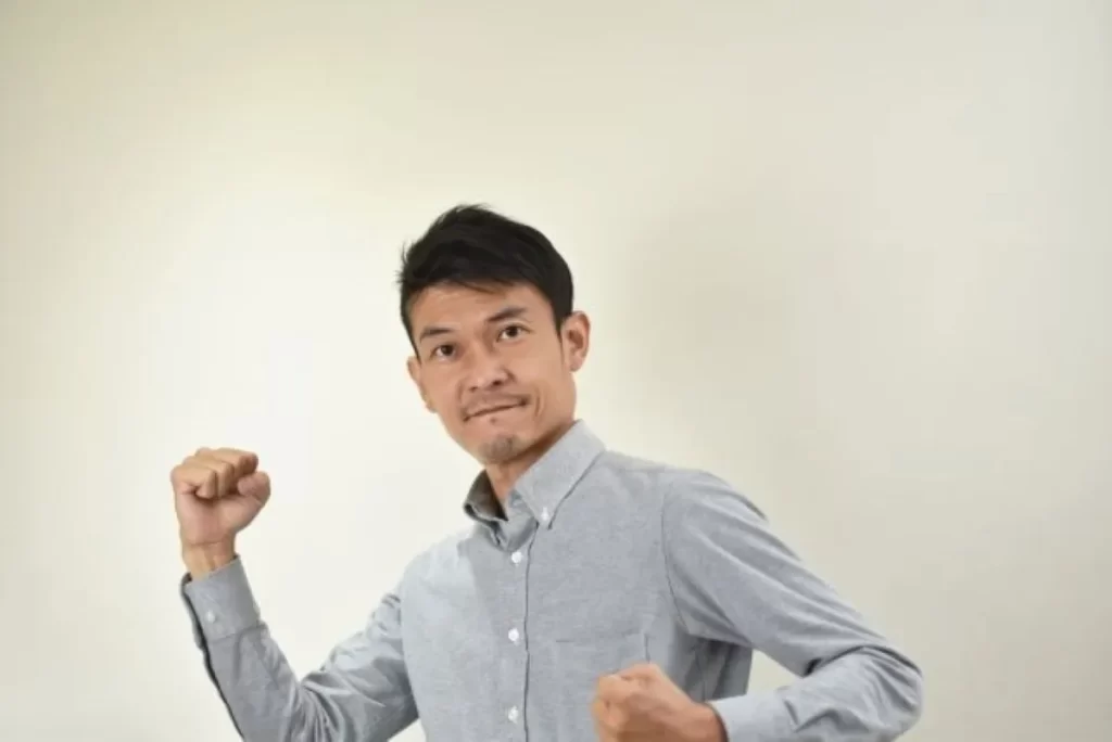 疲れやすさが改善してガッツポーズするグレー長袖シャツの男性