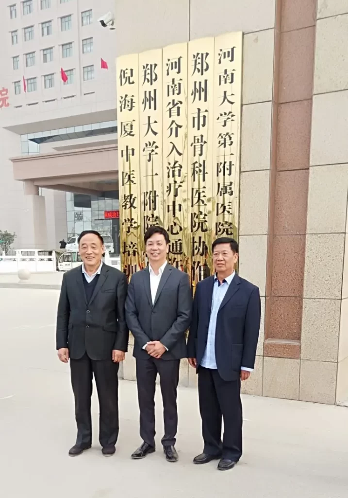 病院前で立つ3人の男性、真ん中が李宗恩博士のグループ写真