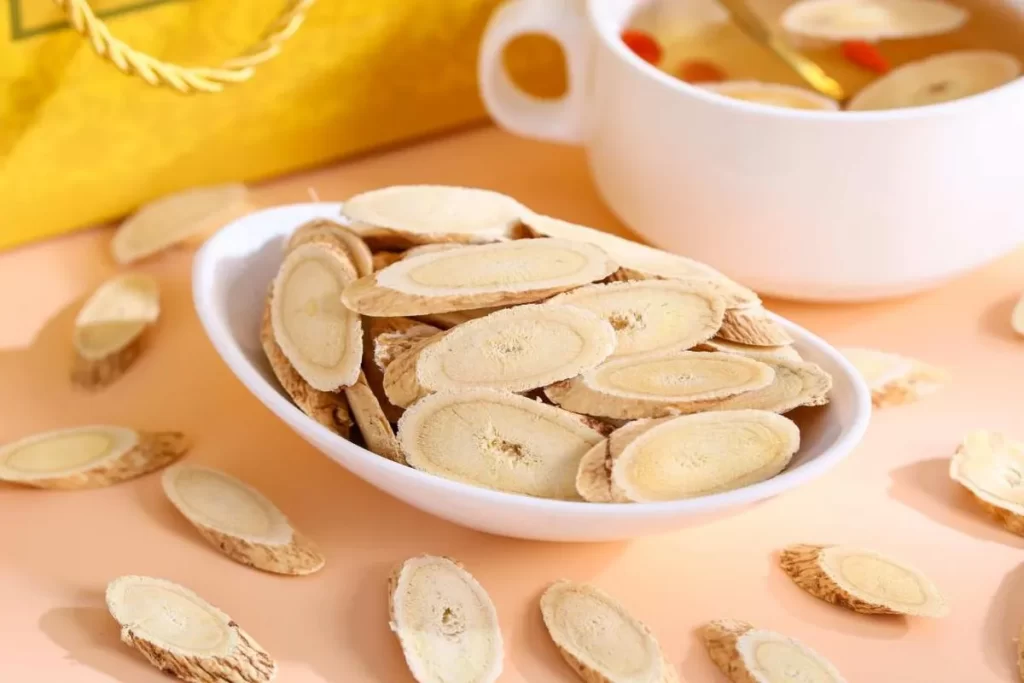 白い皿に盛った切り黄耆と、奥に黄耆とクコの実を煎じた漢方薬の煎じ汁