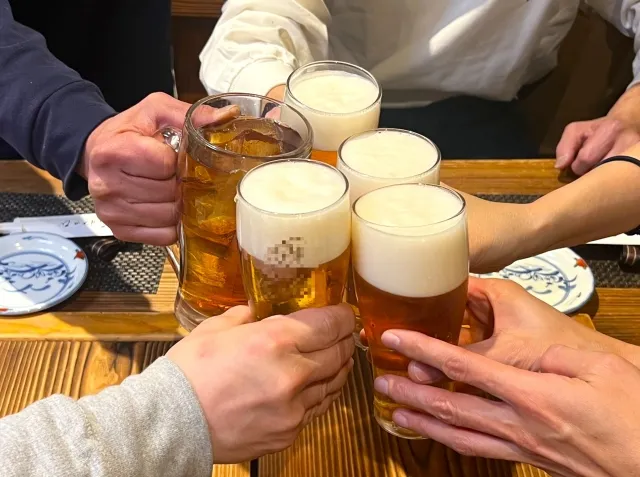 お酒を飲み過ぎる宴会のシーン（ビールで乾杯する手元）