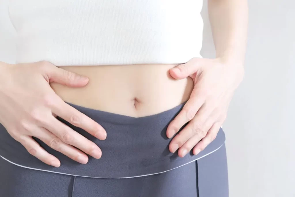 生理の不正出血やお腹の痛みに悩んで両手でお腹を抱える女性の手元