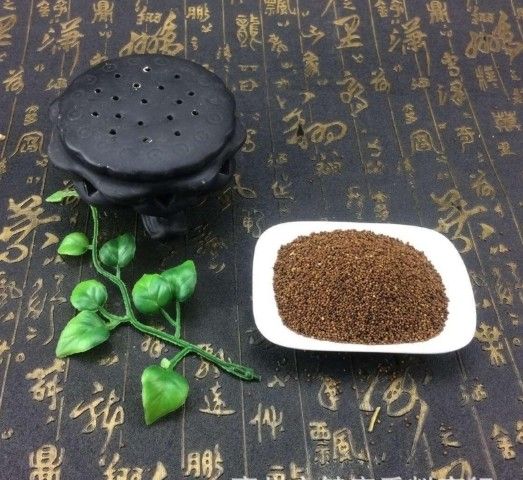 漢字が書かれた黒いテーブルの上に菟絲子の葉と実が盛られた皿。漢方薬でうつ病、便秘、頭痛を改善。