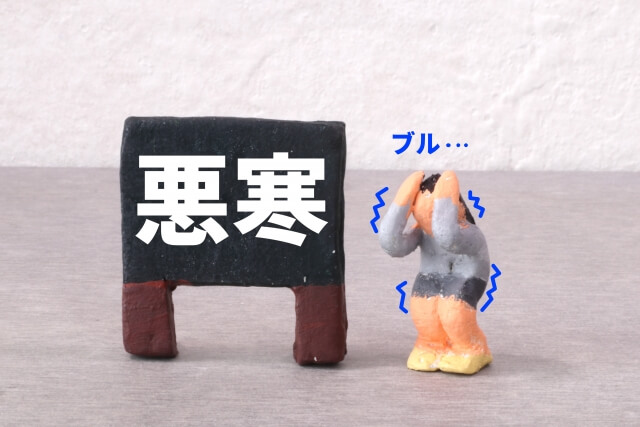 黒い看板に『悪寒』と大きく書かれ、その下で人が寒さに震えているイラスト。麻黄湯の効果を象徴。