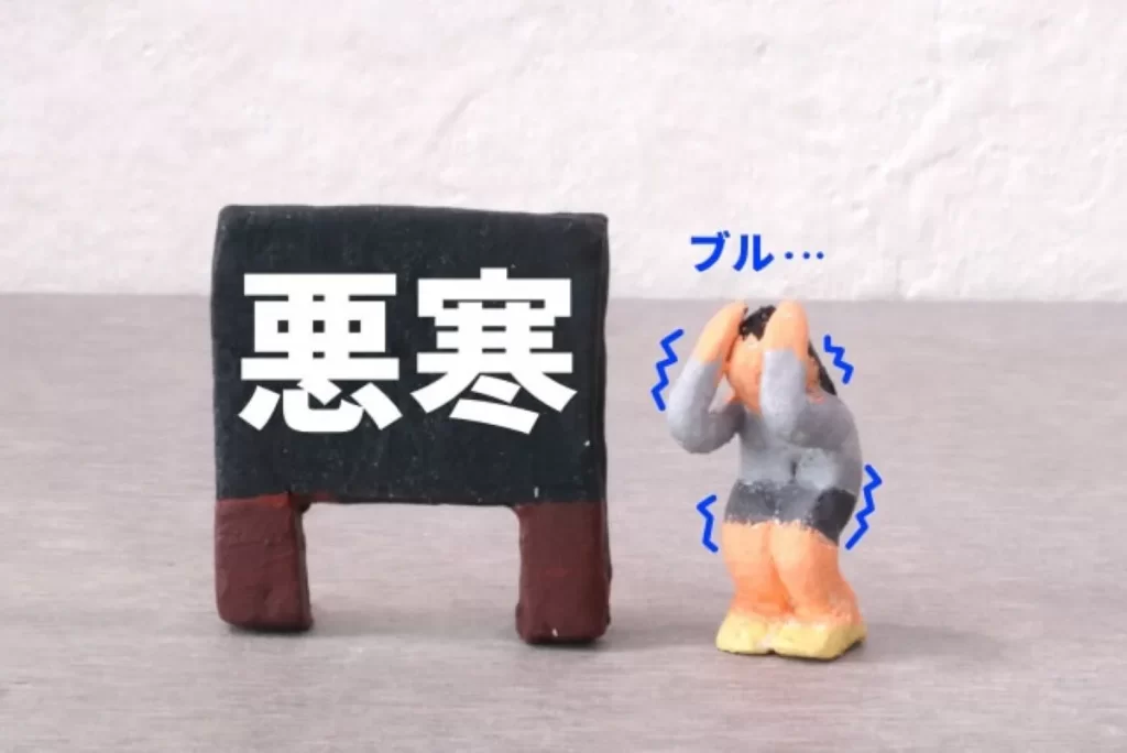 黒い看板に「悪寒」と大きく書かれ、寒さに震える粘土人形のイラスト。麻黄湯が効く悪寒・発熱の症状を象徴