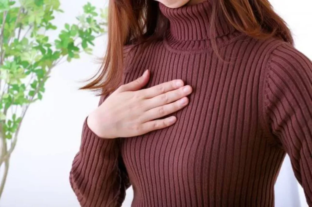 胸の痛みと呼吸困難で胸を押さえる女性の手元のクローズアップ