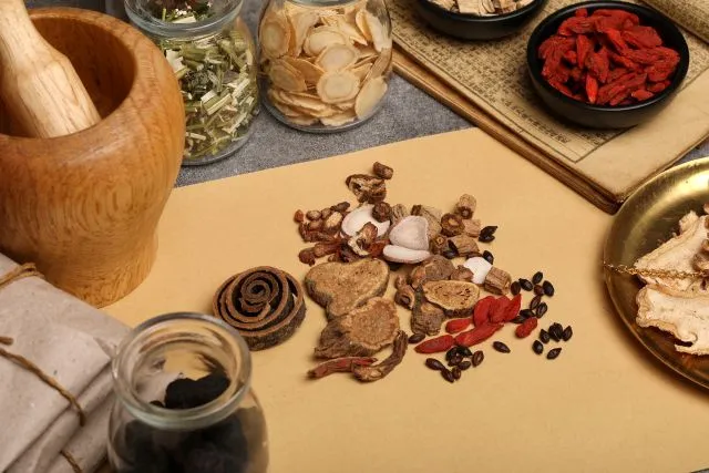 クコの実を含む各種生薬が様々な容器に並び、漢方薬の古い秤、古本、包装紙に包まれた生薬、砕く道具などが写った伝統的な漢方薬局の様子。