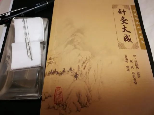 鍼灸大成の本と伝統的な鍼灸道具：鍼、綿、金属皿、ボールペン