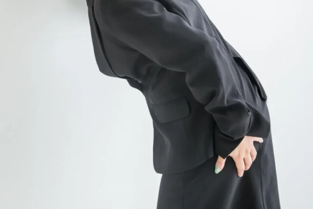 慢性的な下痢で便意を我慢しながら前かがみになるスーツ姿の男性