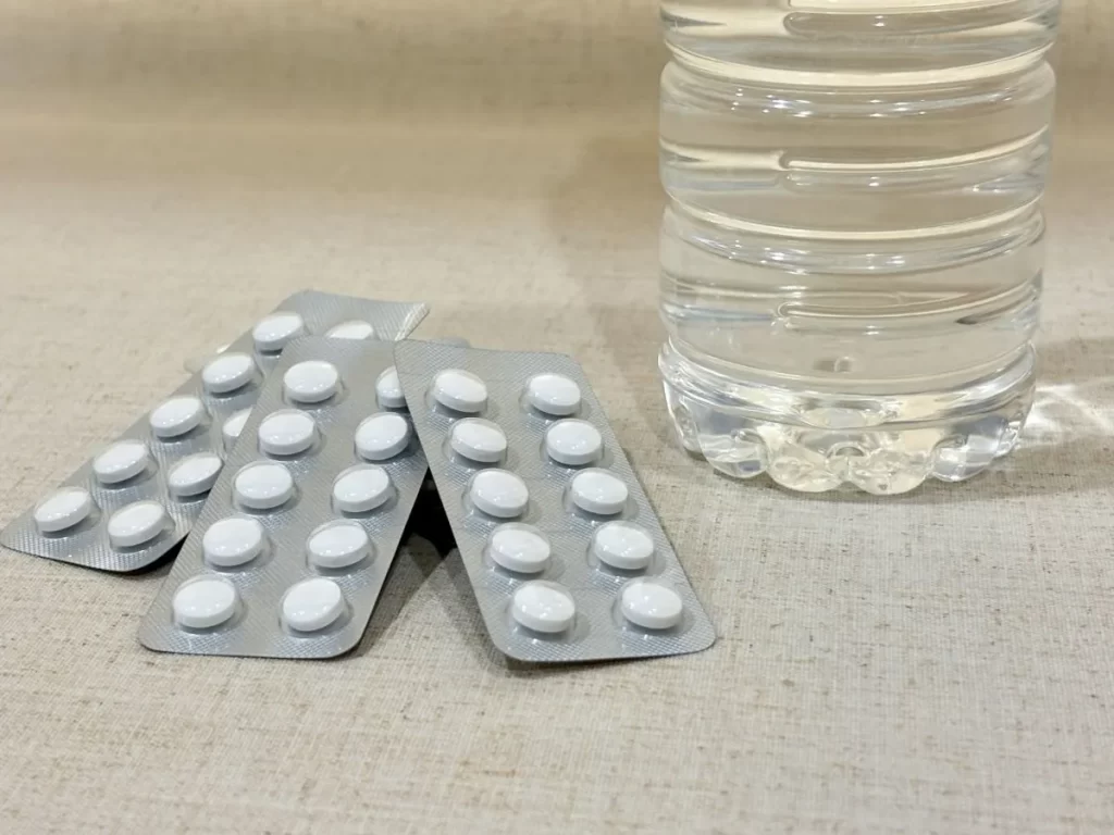 白い抗生物質のパッケージとペットボトル水。病院の薬では滲出性中耳炎が完治しなかった例
