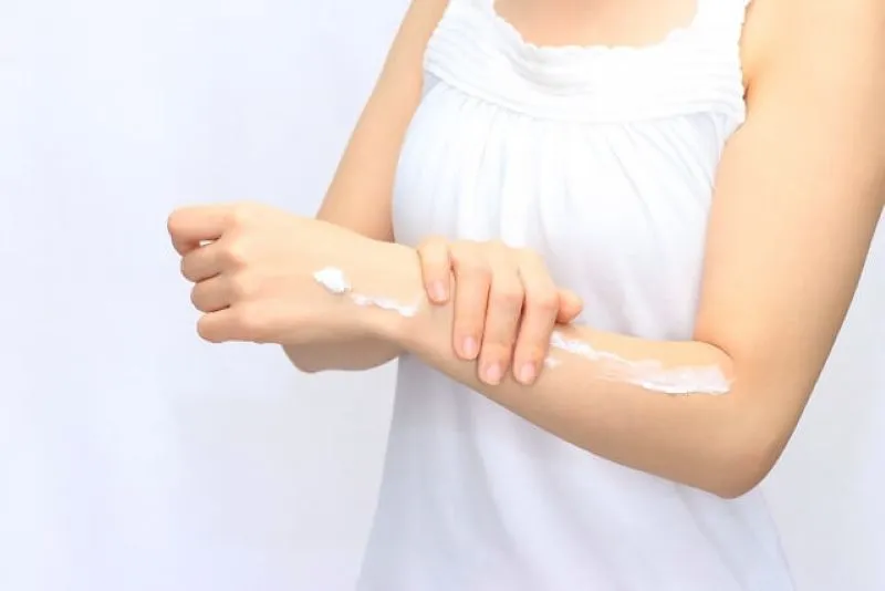 女性が左腕に日焼け止めクリームを塗っている肩から手までのクロースアップ