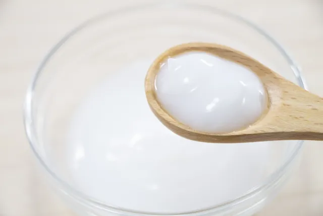 透明容器に入った白いラード（豚脂）をスプーンですくっている画像。漢方「猪膏髪煎」の主成分