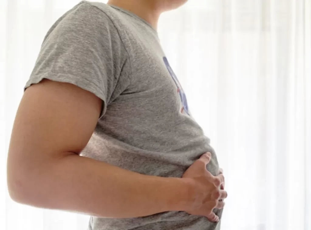お腹が張って苦しむ男性の手元のクローズアップ