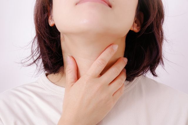 甲状腺の腫れを気にする女性が首を触る様子