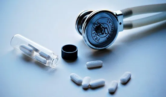 透明な薬瓶からこぼれる錠剤と聴診器、プラセボ対照試験を象徴