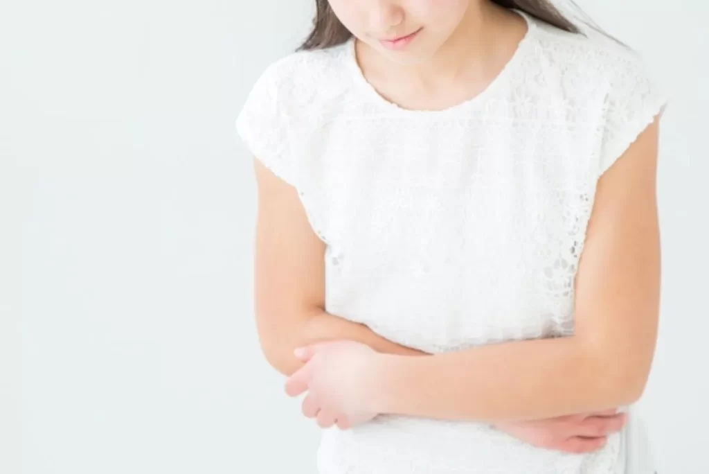 みぞおちの痛みを両腕で押さえている16歳少女の様子（心臓に近い位置の痛み）