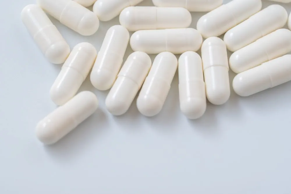 抗うつ剤の白いカプセルが大量に並んでいる画像。向精神薬の過剰処方を示すイメージ