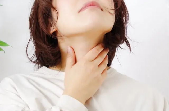 女性が喉の違和感を気にして首を触る様子