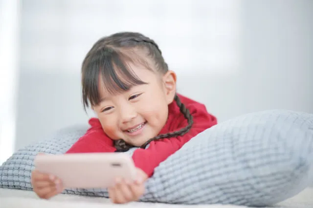 スマホを持って笑顔で楽しそうに見ている女の子。鍼治療直後の様子を表現。
