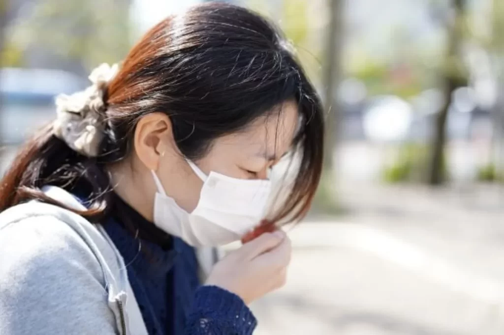 コロナ後遺症で咳き込む女性 マスク姿の横顔 右手で口を押さえて苦しむ様子