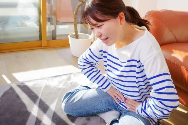 産後の恥骨痛に悩む女性が下腹部を両手で押さえている様子