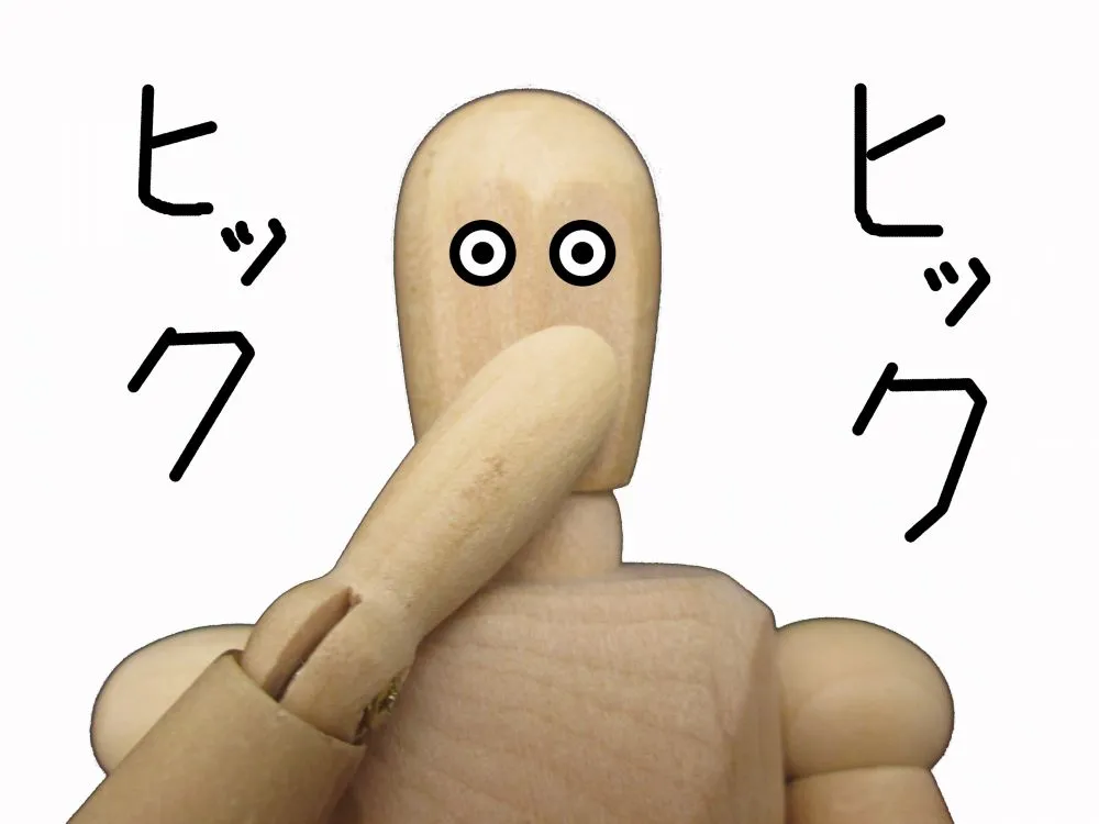 目を大きく見開き口を塞ぐ木製人形の驚きのイラストと「ヒック」文字。長年のしゃっくりの雷鳴のような症状を表現した画像。