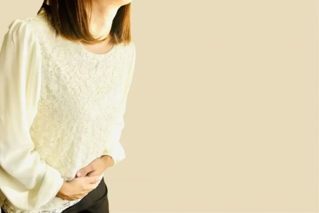 右下腹部を両手で押さえて痛みを感じる女性の写真