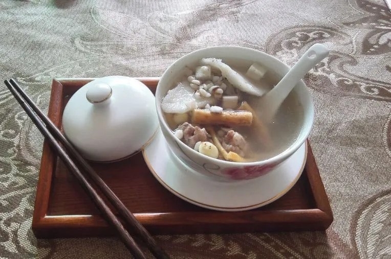 木製トレイに置かれた白い茶碗に入った出来上がり四神湯と箸