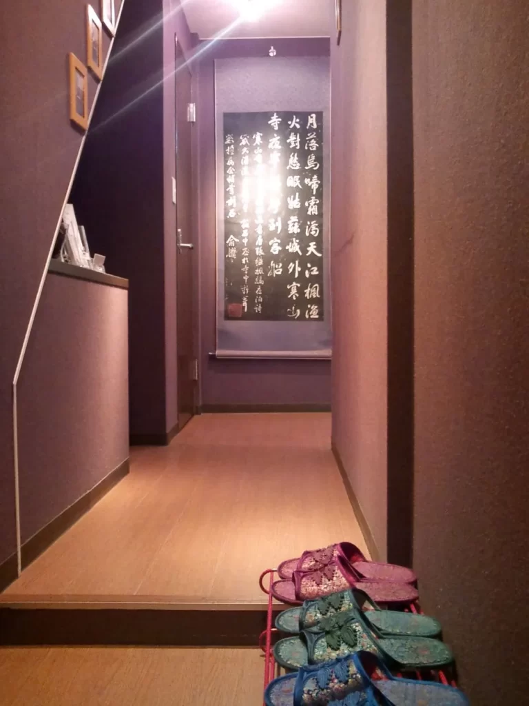 プライブケアの入口。中国風スリッパと漢詩掛け軸のある細い廊下。