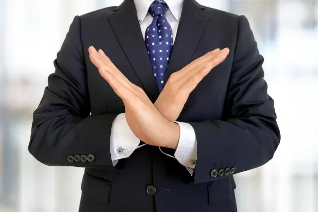 腕でバツを作っているビジネスマン