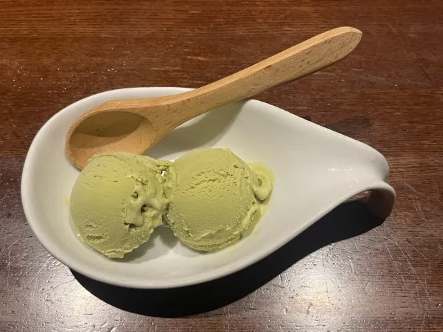 白い皿に盛られた抹茶アイスクリーム2スクープと木のスプーン