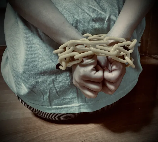 鎖で後ろ手に縛られた人のシルエット（誘拐監禁イメージ）