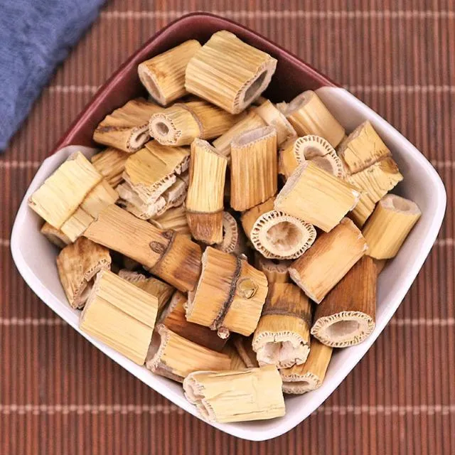 白い陶器の皿に盛られた切断された苇茎(いけい)の中薬材