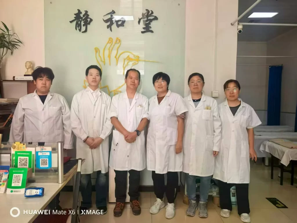 張静先生の診療所「静和堂」のスタッフ全員と研修生の李哲が揃って撮った集合写真。みんな笑顔で、背景のガラス看板に「静和堂」のロゴが輝いています