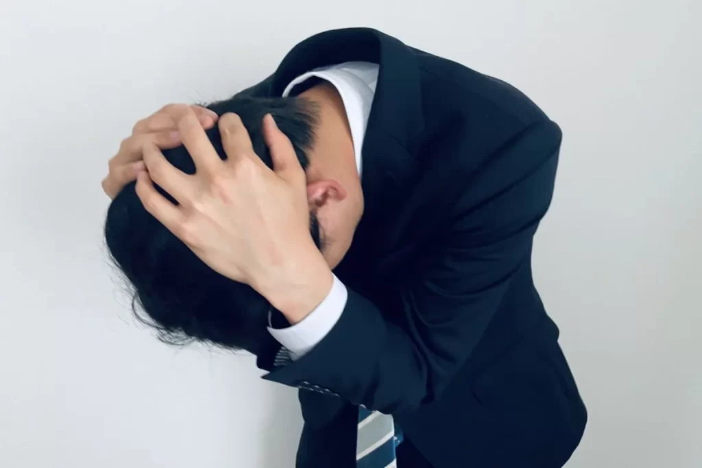 後頭部神経痛で後頭部を抱えて頭を下げて苦しむサラリーマン