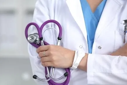 白衣の男性医師が胸の前で手を組み、聴診器を持っている様子