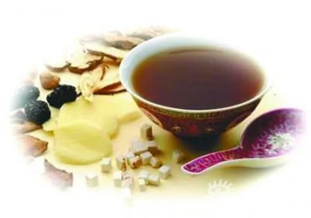 煎じ薬の入った茶碗と紫色のスプーン、生薬が散らばった写真