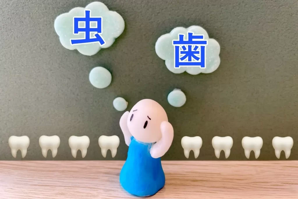 困った表情で両手を上げる人形と「虫歯」の文字、背景に歯のイラストが並ぶアイキャッチ画像