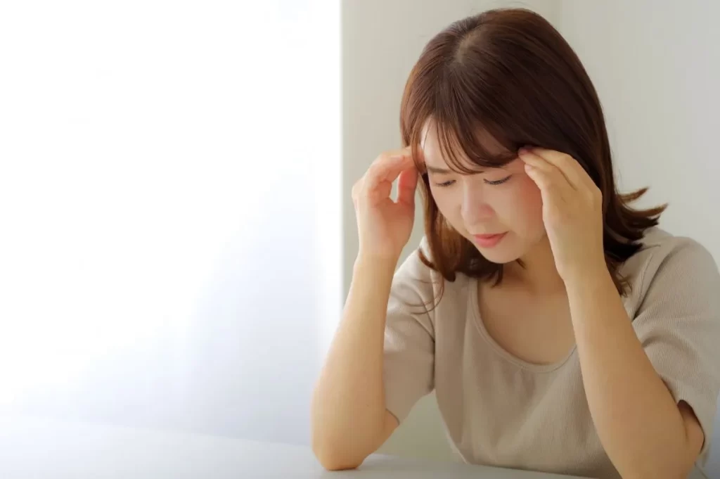 貧血でめまいがして頭を押さえる女性