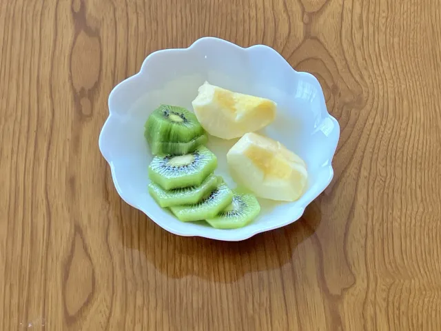 果物のキウイとりんごが白い皿に盛られている朝食の写真