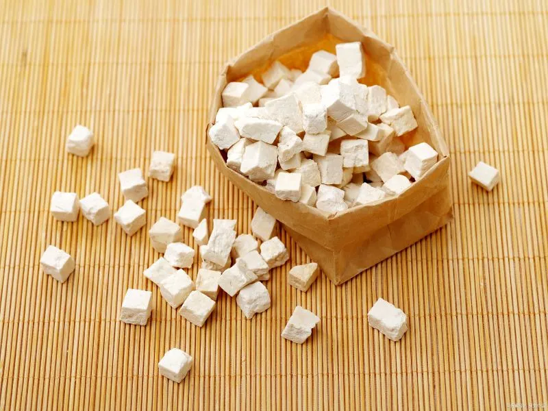 土色の紙袋に盛られた白い四角い生薬の茯苓(ブクリョウ)